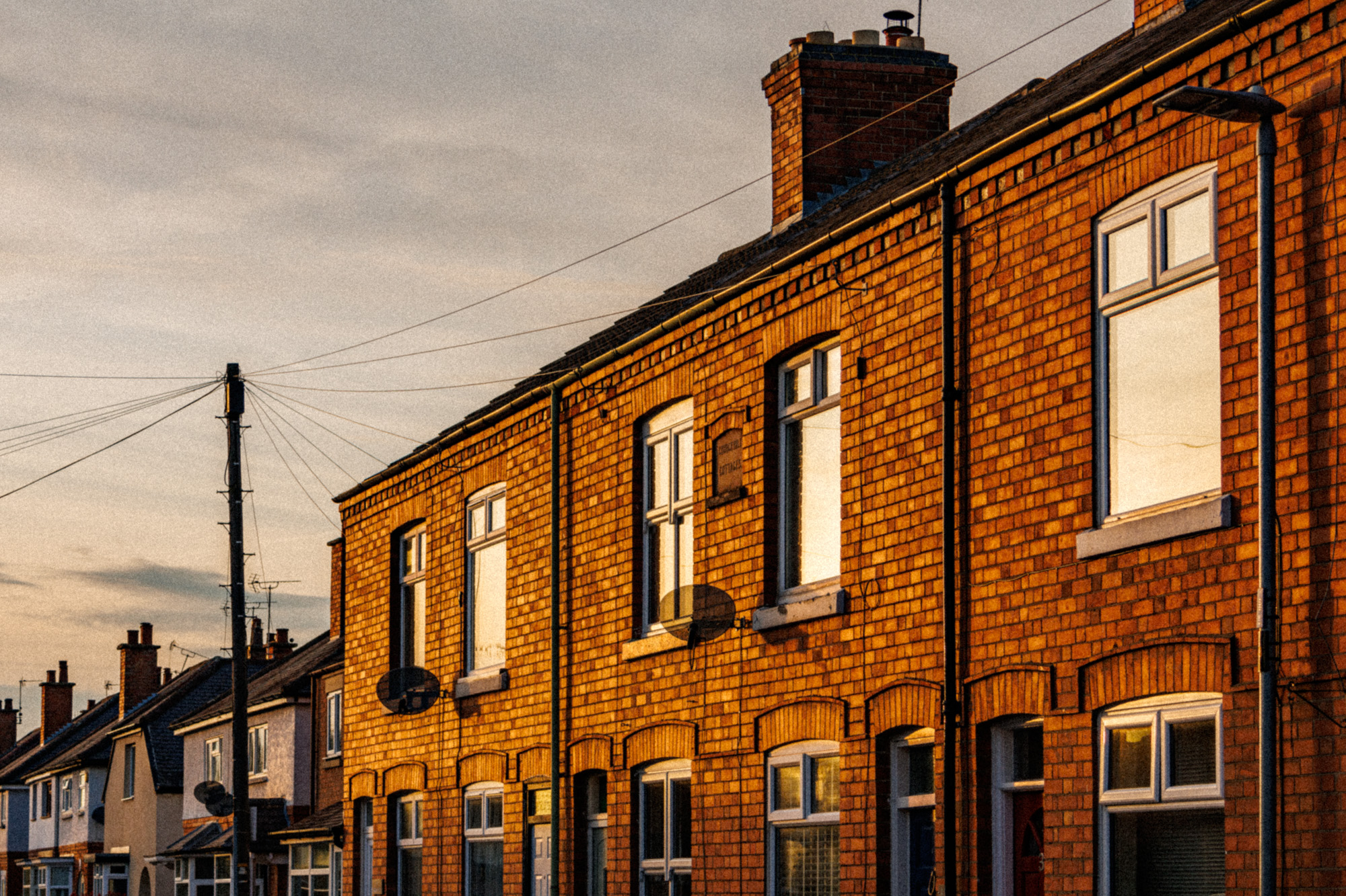 A grainy photo of a row of houses lit by the orange glow of a sunset