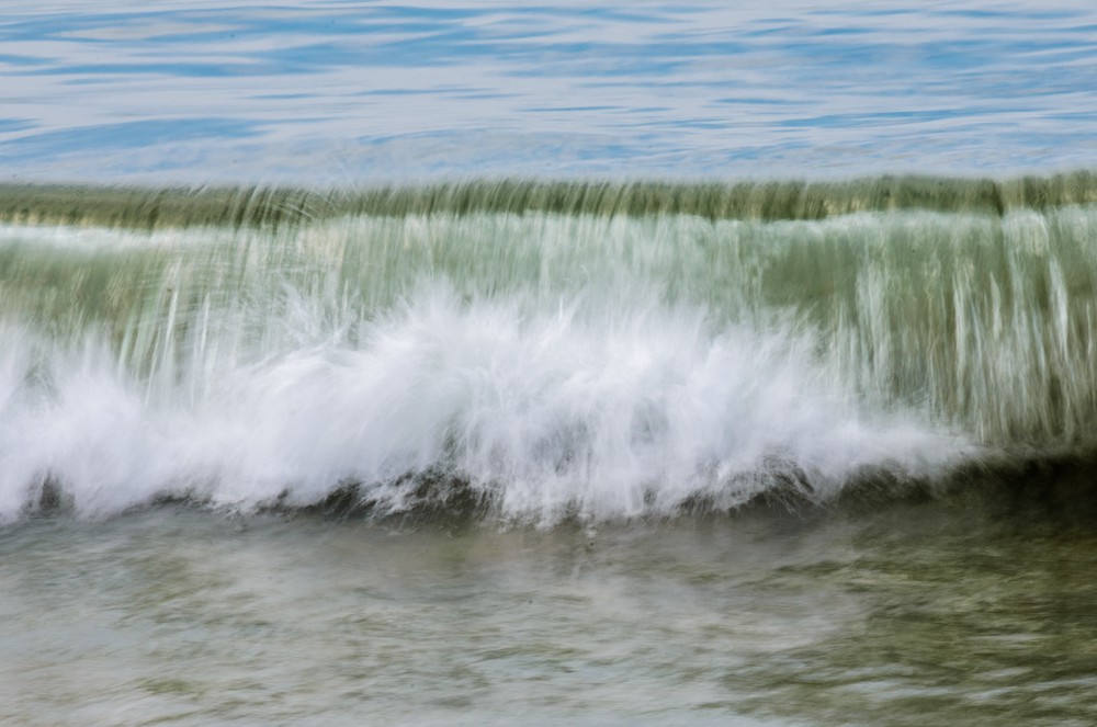 A blurry wave crashes in the sea.
