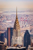 In the center stands the spire of Chrysler Building with its glowing gloden arches and arrows pointing to the sky. Around it are more skyscrapers and other tall buildings. The background is washed out and orangey suggesting the the photo is old.